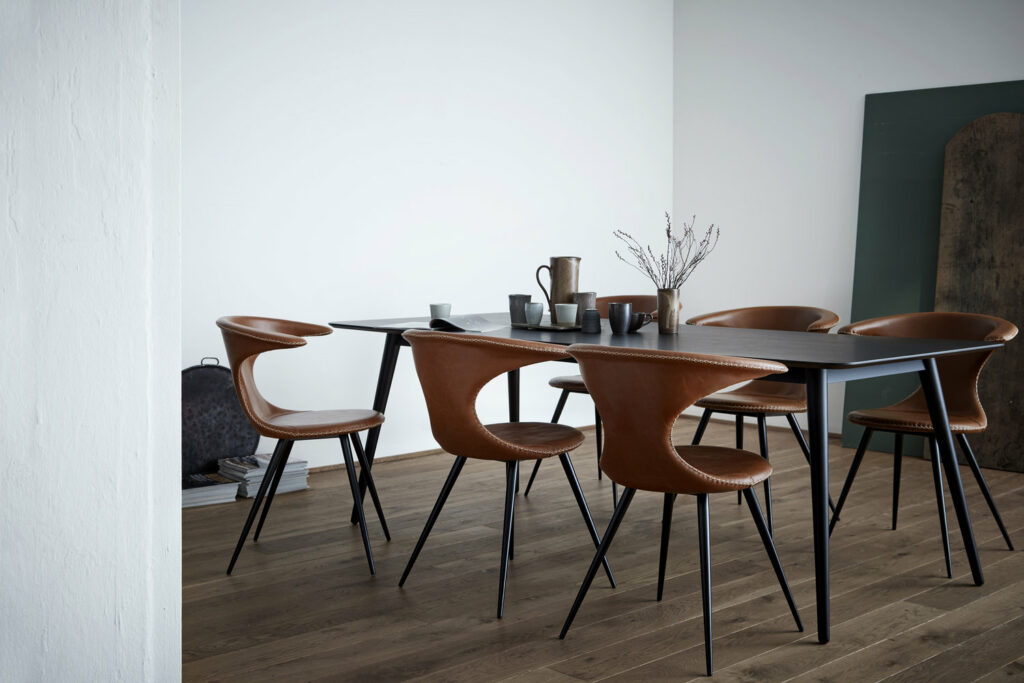 שולחן אוכל מעץ צבוע בשחור בשילוב כיסאות בשילוב עץ ועור בגוון חום חמים, בעיצוב "דן פורם", דנמרק
