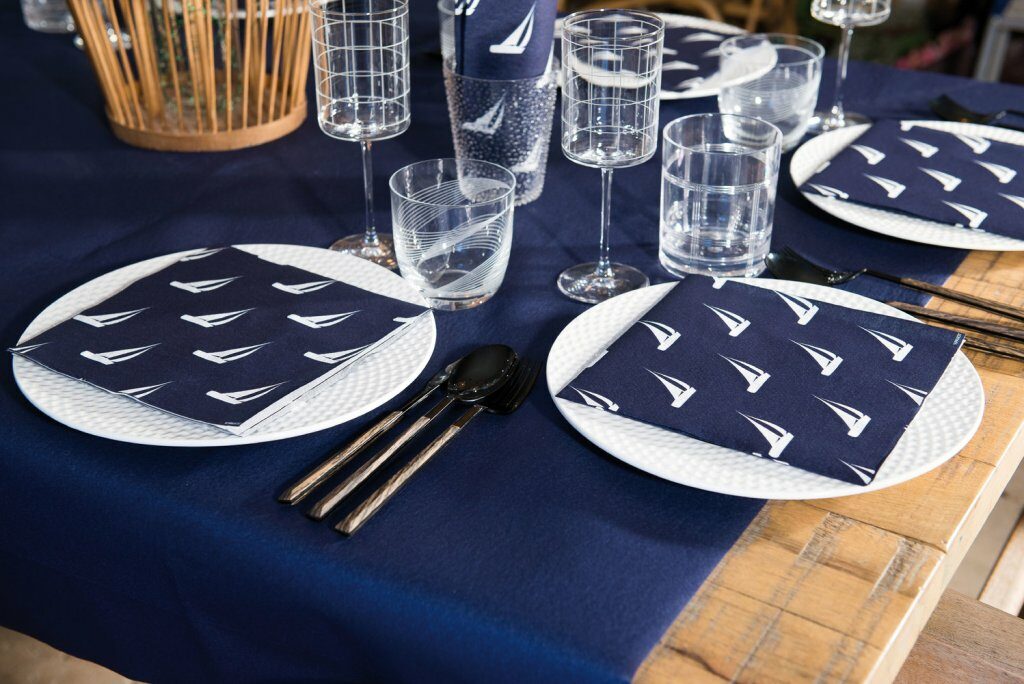 אם רוצים אווירה של חוף ים, אפשר לפרוש על השולחן ראנר כחול, להניח עליו כלי אוכל לבנים ושקופים ולשלב מפיות בהדפס מפרשיות