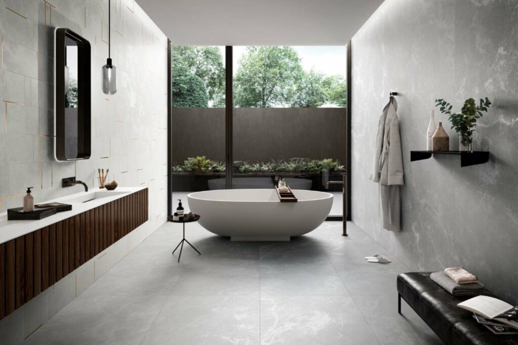 חלל אמבטיה במראה תעשייתי עם קיר בטון וקיר בחיפוי אסימטרי ואמבט פרי סטנדינג, בעיצוב "קרמיק רפין", איטליה