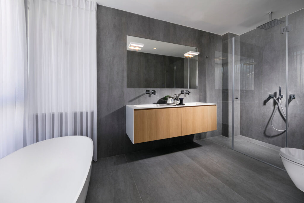 חדר אמבטיה גדול הכולל מקלחת זוגית, יחידת ארונית זוגית ואמבטיית פרי-סטנדינג המשקיפה אל הבריכה